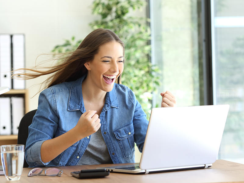 Excited small business owner working on a laptop and the hair moved by the wind